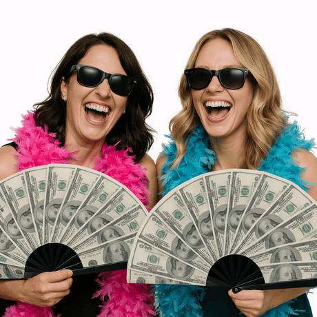 Two women in sunglasses laughing while holding Money Photo Booth Props resembling fans made of cash.
