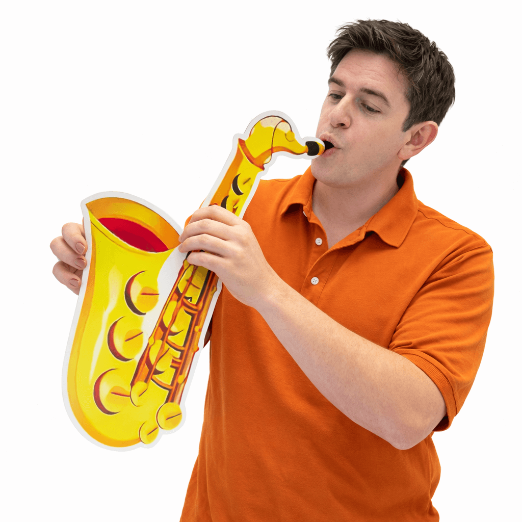 Man holding oversized photo booth props saxophone, celebrating at a party with fun decorations.