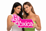 Women holding La Toxica Big Individual Prop sign in bright colors, showcasing fun and quality design.