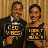 Two smiling individuals holding black and gold photo booth props that say 'CEO VIBES' and 'I DON'T READ EMAILS'.