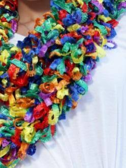 Colorful featherless boa made of soft polyester with vibrant curls, worn on a white shirt, showcasing its beauty.