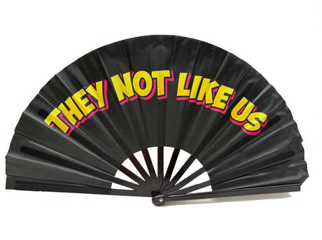 Colorful folding fan with 'THEY NOT LIKE US' text, great for events and props, 13 inches tall.